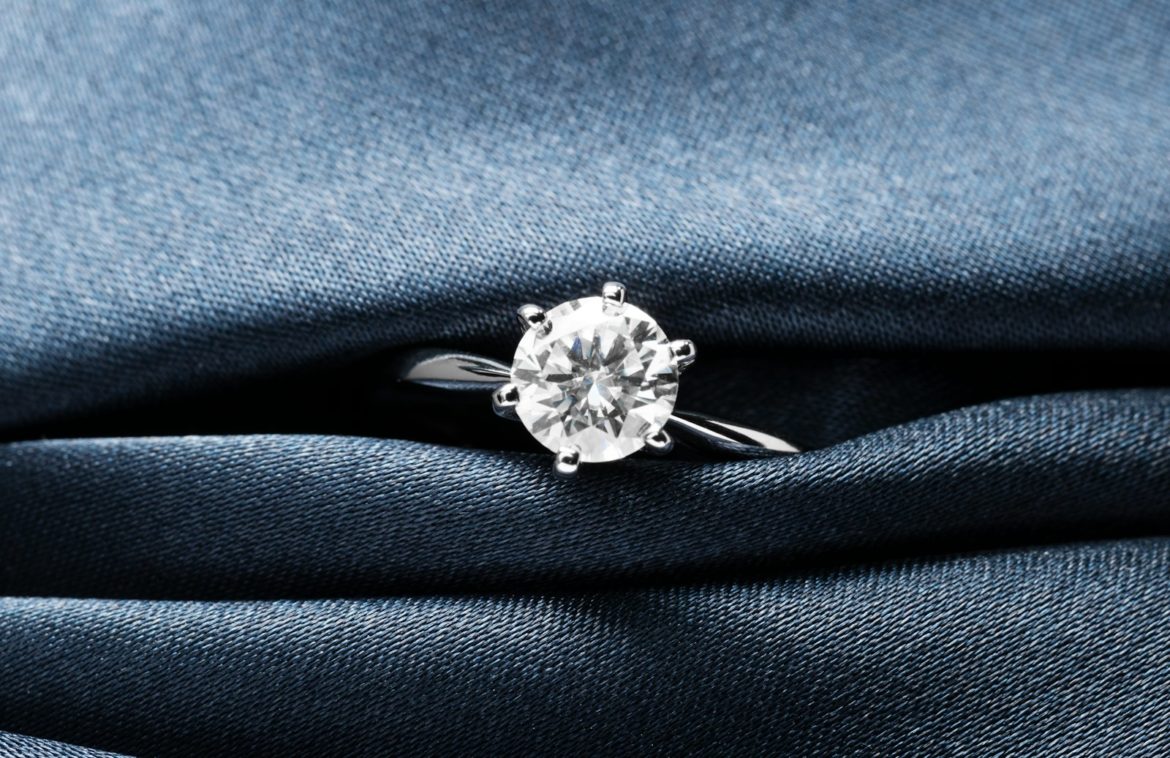 A close up of a diamond ring on a blue cloth